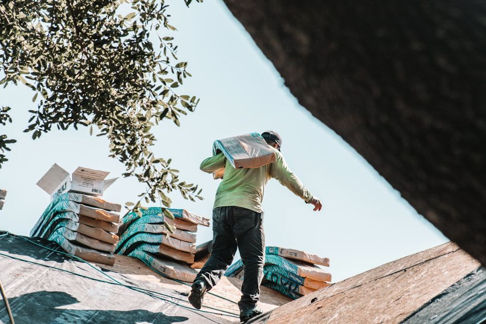 Roofer carrying shingles on a roof