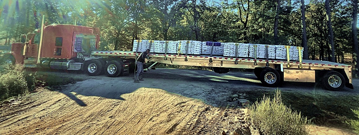 Red semi with a flatbed loaded with pallets of our shingles